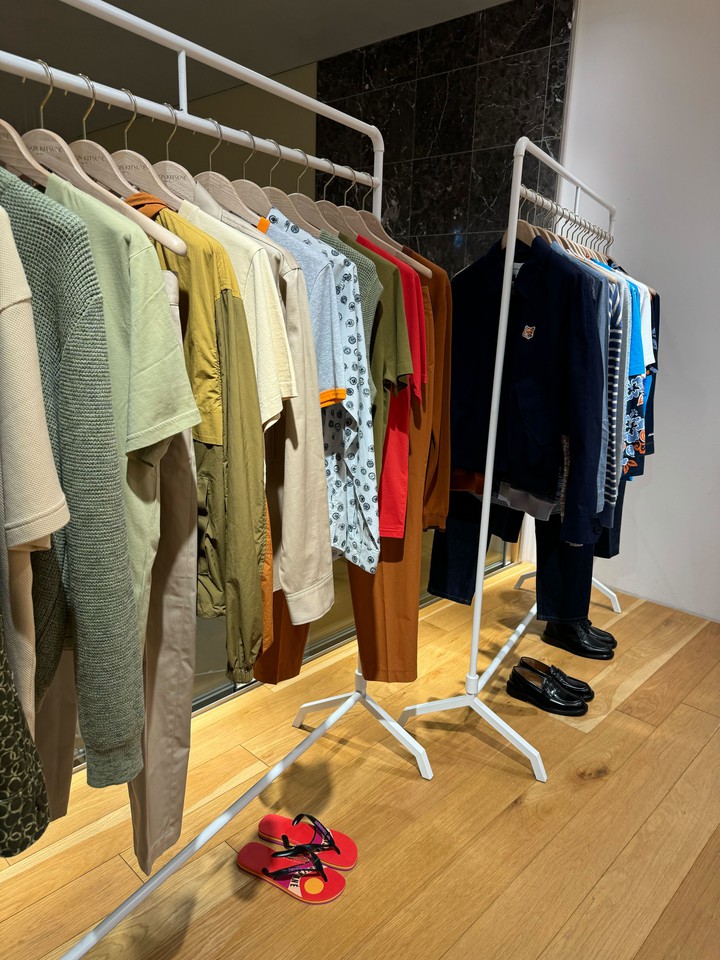 カジュアルな衣類が並べられたメゾンキツネの店内レイアウト、足元には赤いサンダルが一足。