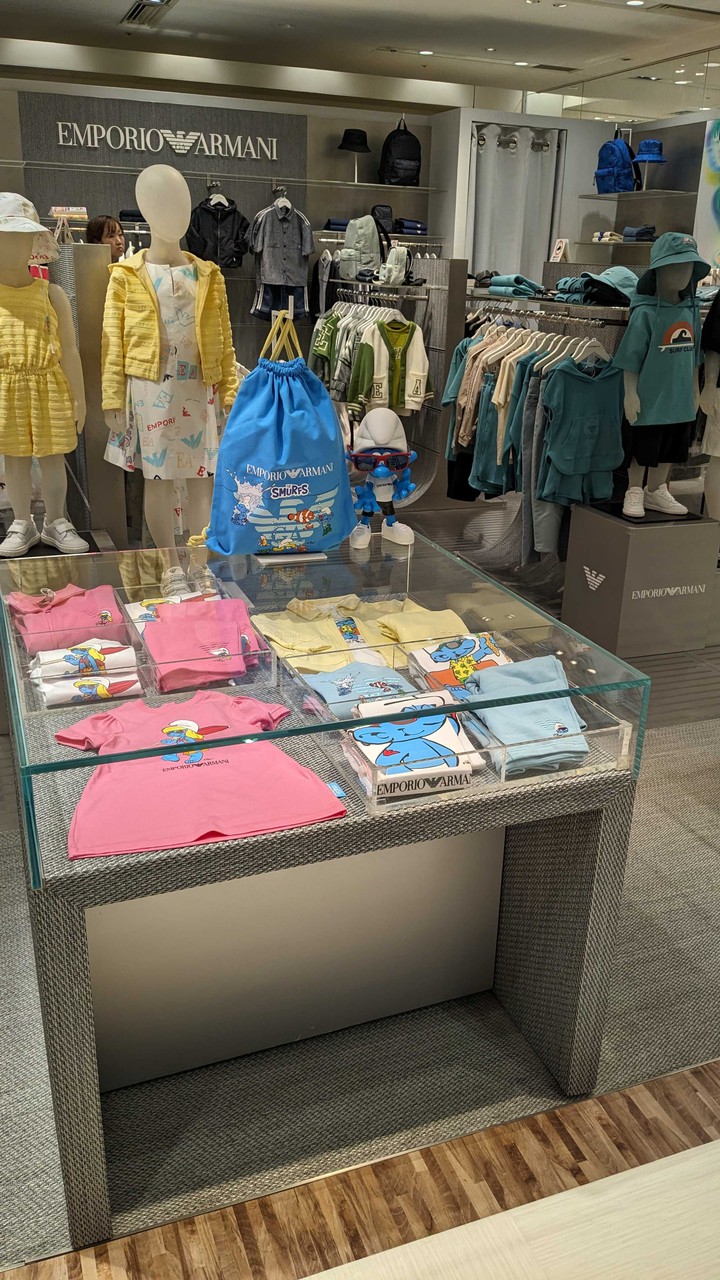 ガラスケースの中に並べられたエンポリオアルマーニジュニアのカラフルな子供服。キャラクターがデザインされたTシャツが目を引きます。