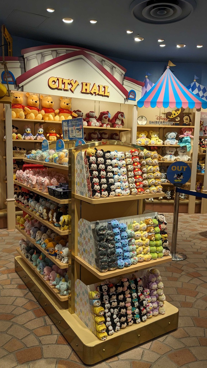 Disney storeで多彩なキャラクターのぬいぐるみが並び、特にツムツムシリーズのぬいぐるみが目立つ展示棚