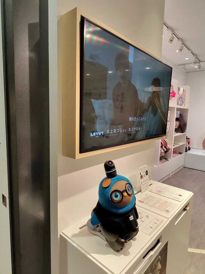 ロボットが置かれているディスプレイ台。壁にはモニターがあり、ロボットの解説動画が流れている