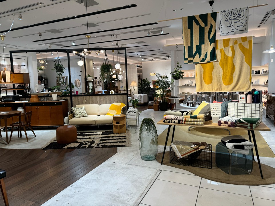 明るい店内にモダンな家具とアクセントの黄色いタオルが映えるジャーナルスタンダードファニチャー。