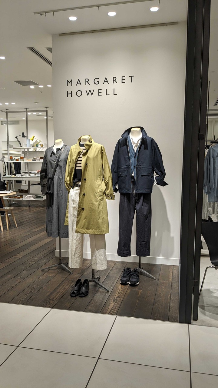 明るい照明の下、マーガレットハウエルの店内で展示されている服。