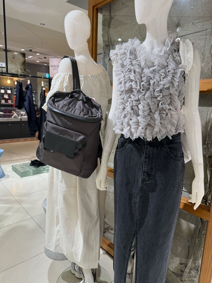 マネキンが現代的なデニムとフリルトップスを着用し、バックパックを展示する店内ディスプレイ。