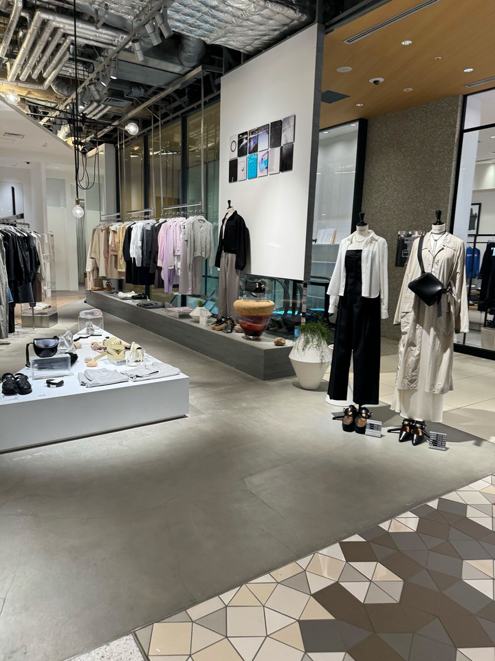 現代的なデザインのアストラット店内で、洗練されたデザインの服がディスプレイされています。