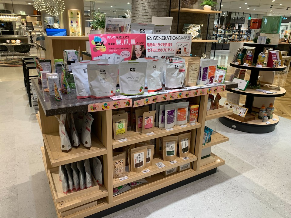 ヘルスコンシャスラボの陳列棚には、プロテインパウダーやオーガニックティーなどの健康志向商品が並びます。