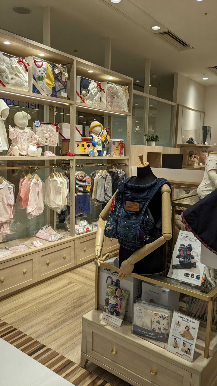 新宿高島屋ハローベビーサロン キッズ向けの服やアクセサリーが整然と並んだ店内。ベビーキャリアを身に着けたマネキンが展示されている。