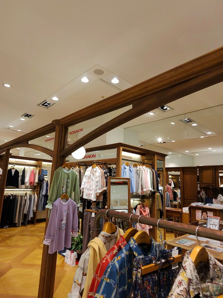 ライトの光が明るい店内で、多様なデザインの衣服が陳列
