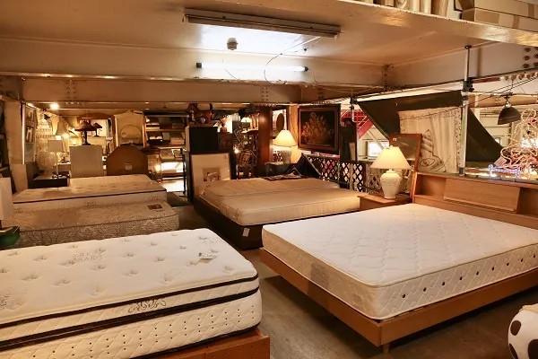 リサイクルショップのベッドコーナー。複数のマットレスとベッドフレームが並んで展示されています