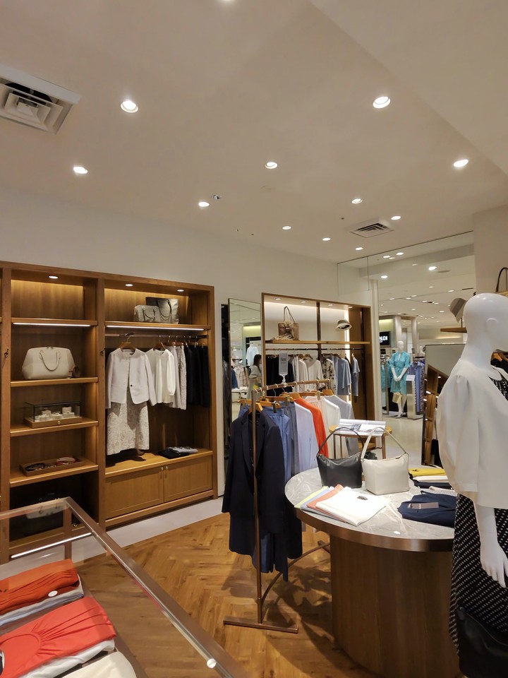 モダンなデザインのPaul Stuartの店内、木製の棚と衣類、バッグが展示
