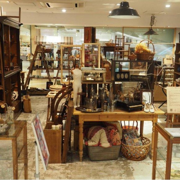 アンティークス・エデュコの店内風景。さまざまな古道具やヴィンテージ品が、木製のテーブルや棚に整然と配置されている