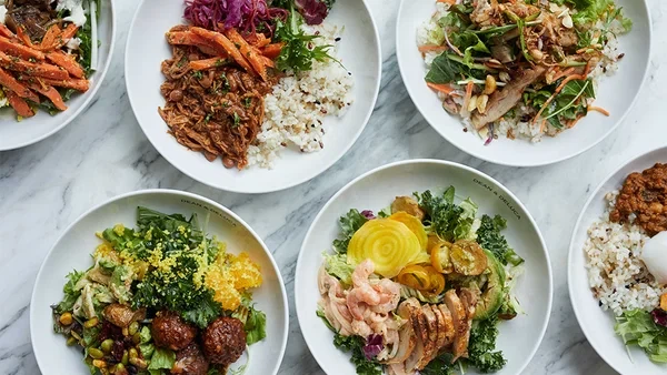 6つの白いプレートに、色とりどりのサラダやご飯が盛り付けられている。それぞれ異なる食材や調理法が使われており、彩り豊かな料理が特徴的な画像。
