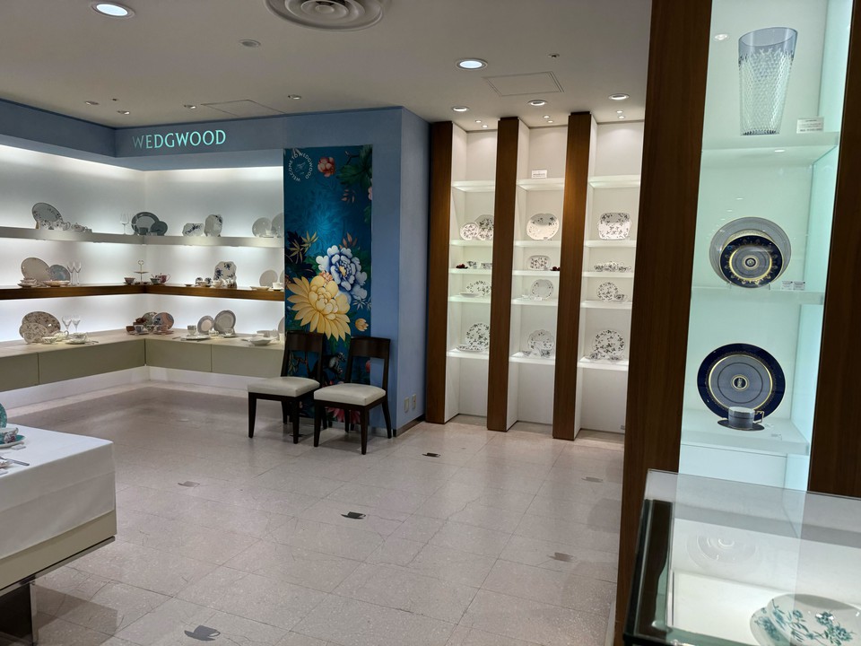 ウェッジウッドの陶磁器が展示されているショールームの内部。壁には青と白の磁器プレートや装飾品が並んでいる。後方の壁にはテーブルウェアが並ぶ棚が見える。