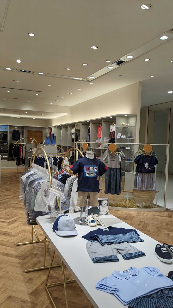 ファミリア店内に展示された子供服のコーディネート例が見えるファミリアの店舗。中央のテーブルには、ネイビーのTシャツやチェック柄のショートパンツが配されています。