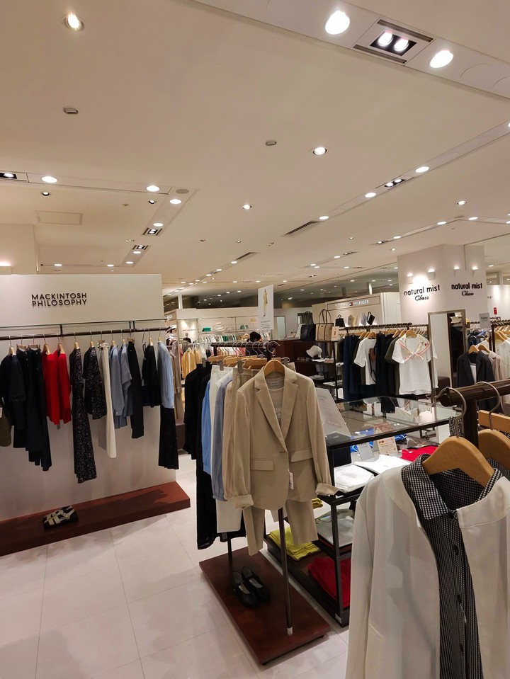 MACKINTOSH PHILOSOPHYと書かれた看板の下で、さまざまなスタイリッシュな服が並べられている。