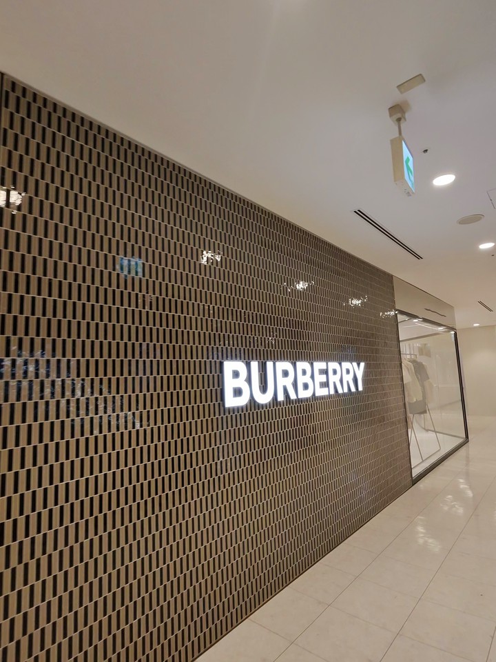 ブラウンの格子デザインの壁に白い光文字で「BURBERRY」と表示されているバーバリーの店舗入口