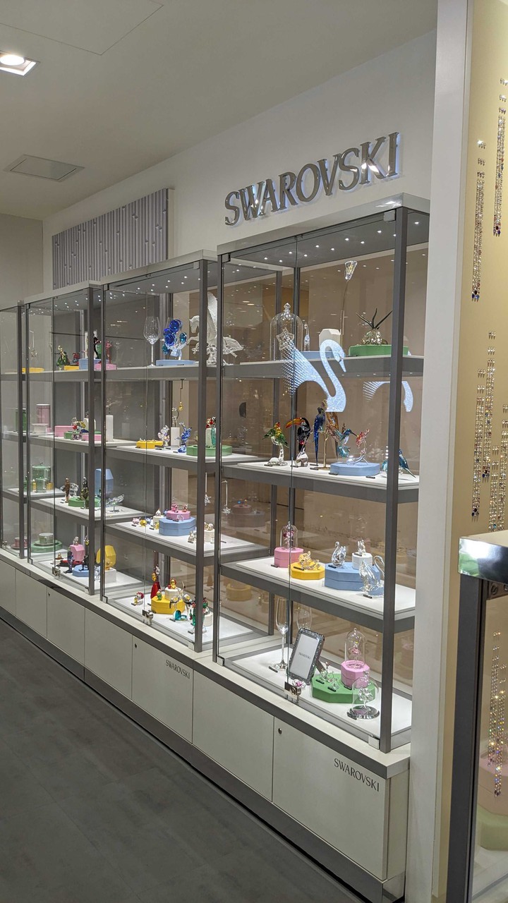 スワロフスキー店内のショーケースに展示された色とりどりのクリスタルフィギュア。上品な輝きを放つデザインの品々が、エレガントな空間を演出しています。