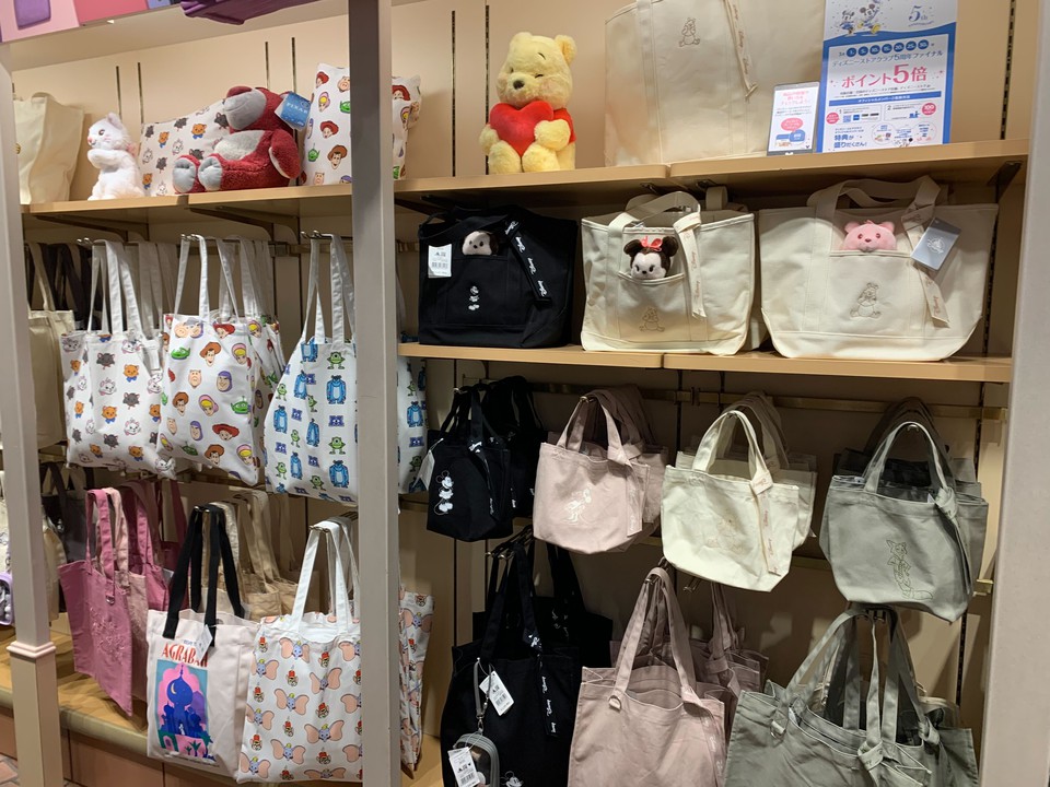 Disney storeでディズニーキャラクターのプリントが施されたトートバッグが棚に並んでいる様子