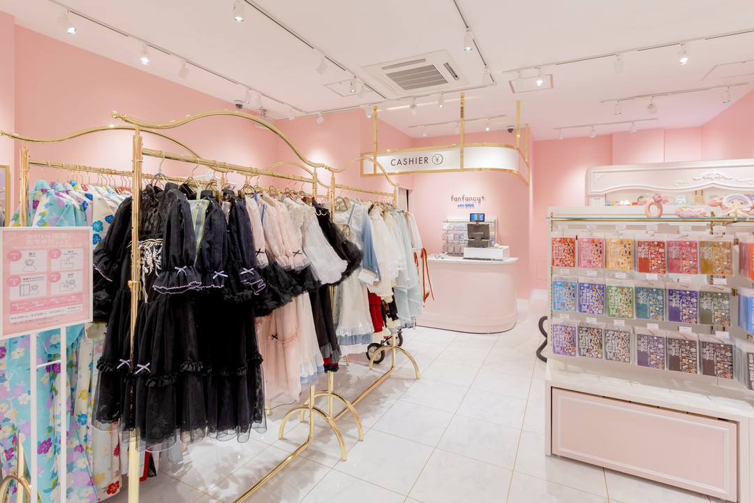 可愛らしいドレスが掛けられたラックとカウンター、ピンクの店内が印象的