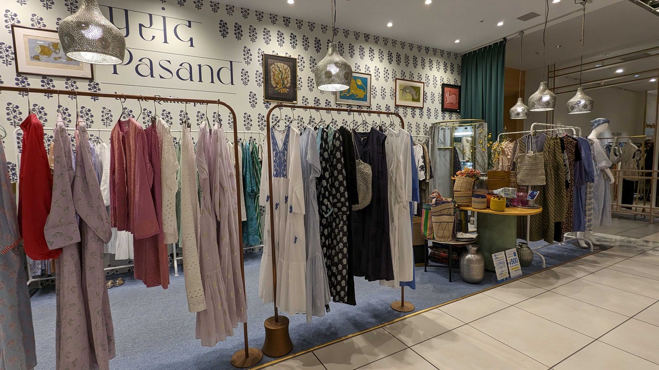 パサンドバイヌキテパの店内で、洋服が掛かったラックと中央のテーブルに飾られたバッグや雑貨が展示されています。