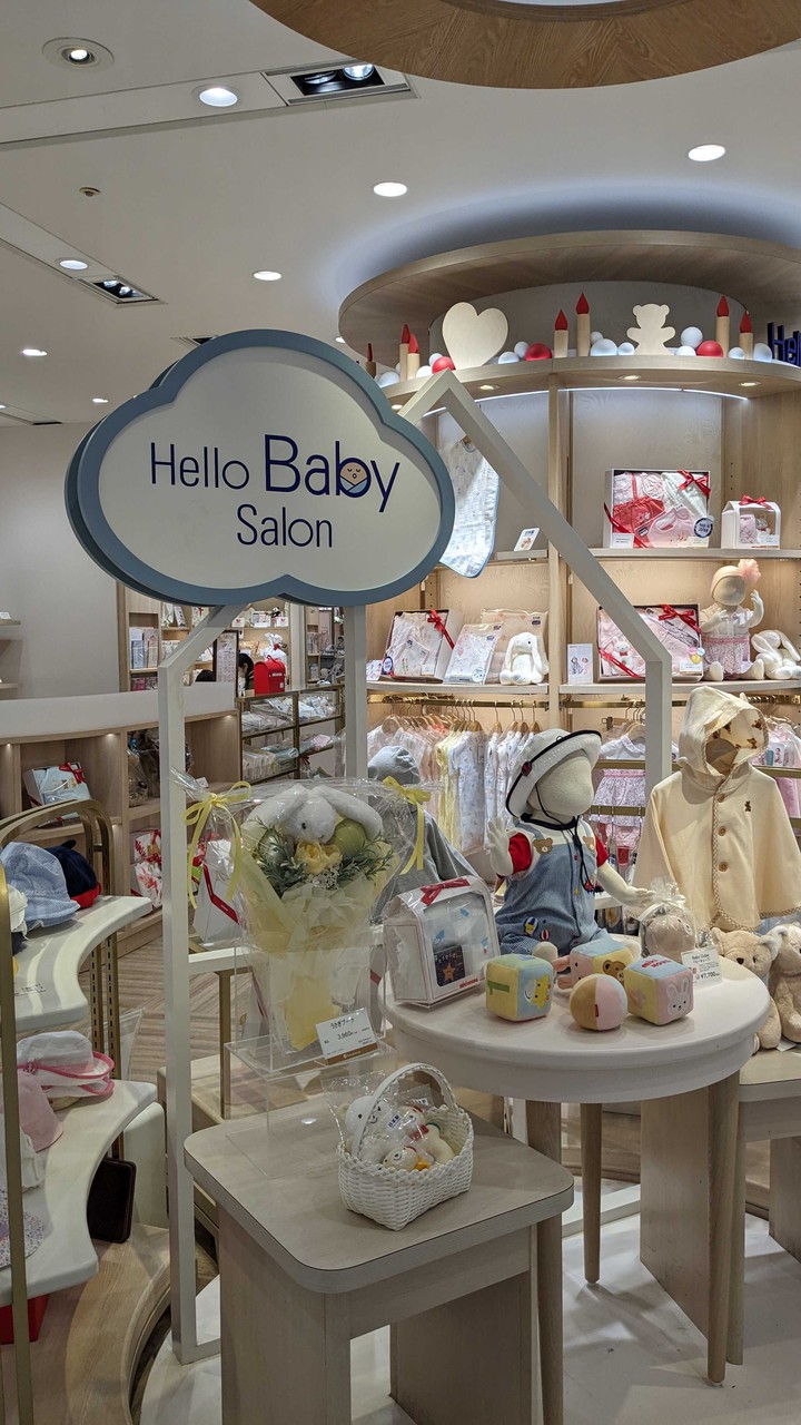新宿高島屋ハローベビーサロン 「Hello Baby Salon」の内装と商品ディスプレイ。赤ちゃん向けの衣類や玩具、ギフトセットがきれいに陳列されている。