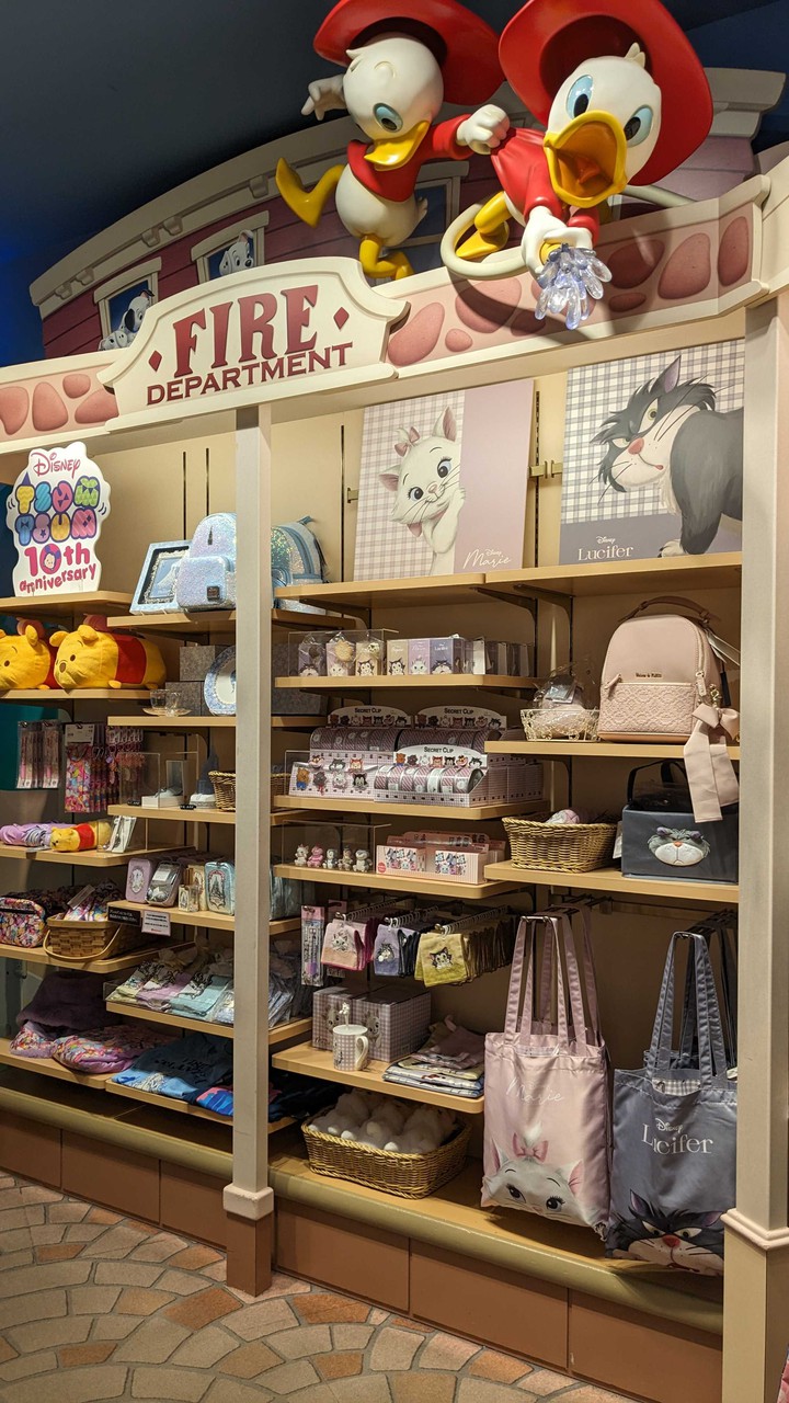Disney storeでディズニーの100周年を祝うバッジと共に、マリーとルシファーのイラストが描かれたグッズが陳列された棚