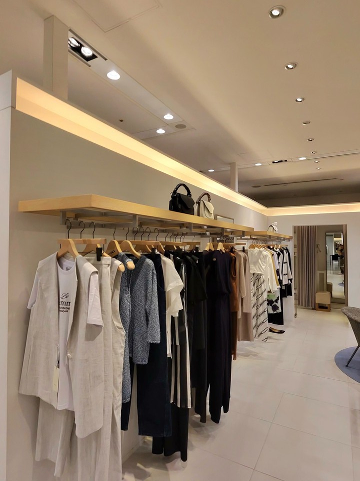 白やグレーの衣類が並んている広々としたモダンなアパレルショップの店内