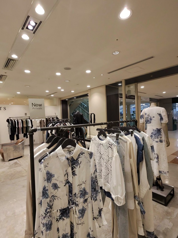 白と青の花柄ドレスやレースのトップスなどが展示されている。オールセインツの店内は広々としており、清潔で明るい雰囲気が漂っている。