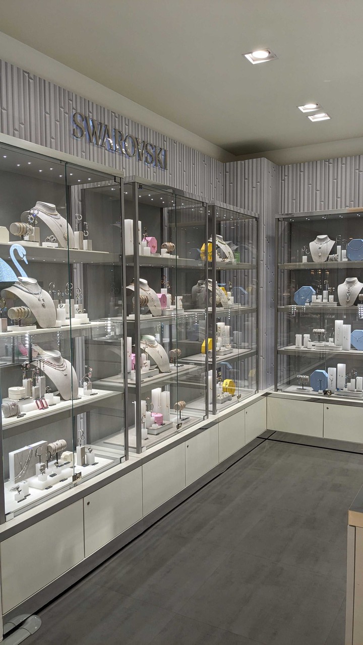 スワロフスキーのショップ内部の光沢のあるディスプレイケースに、エレガントなジュエリーやアクセサリーが並んでいる様子。