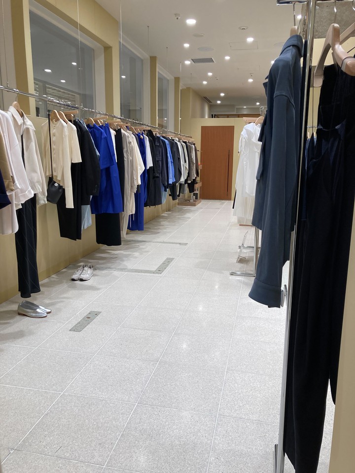 明るい照明と白いタイルのイレーヴ店内に、さまざまなデザインの衣服が整然とディスプレイされています。
