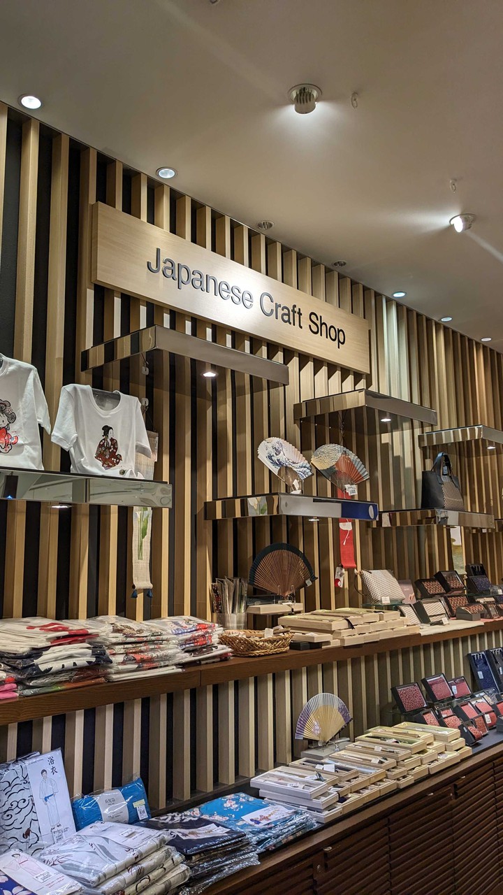 ジャパニーズ クラフト ショップの棚にTシャツ、浴衣、扇子が飾られている売り場