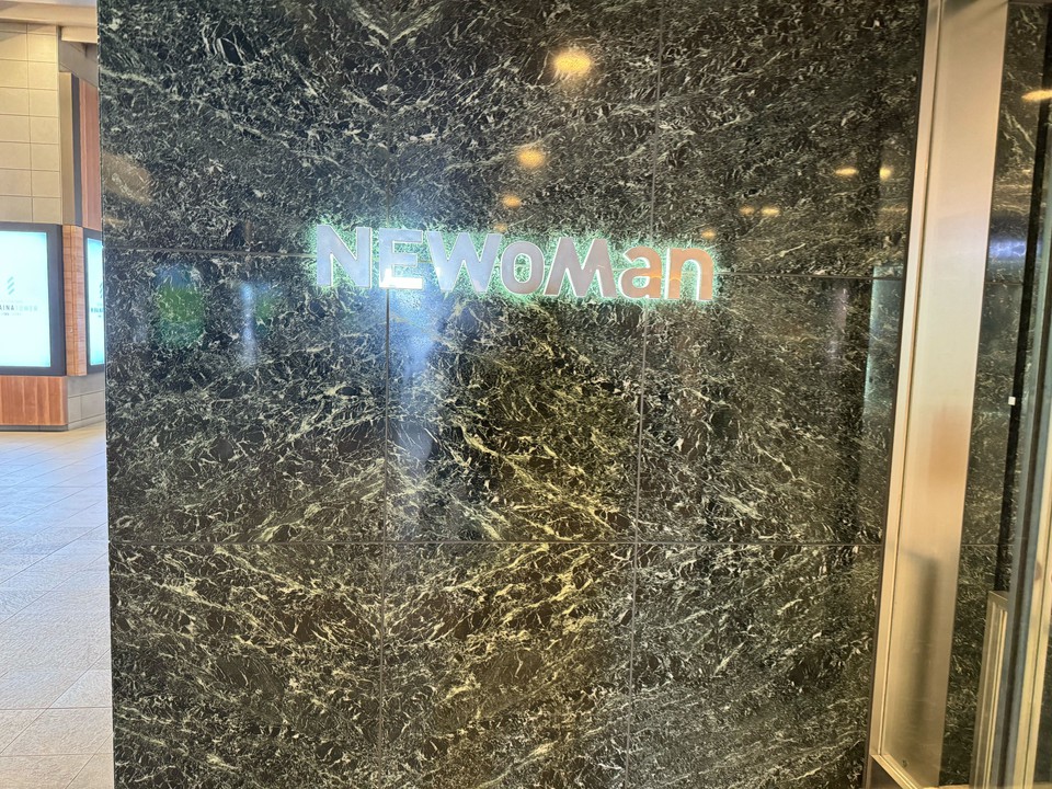 「NEWoMan」の輝くロゴが施された高級感あふれる大理石の壁面。
