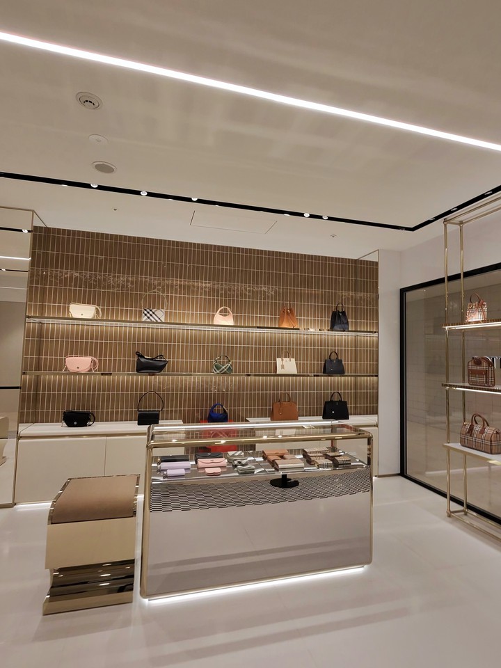モダンなデザインのBURBERRYの店内。壁には茶色のタイル、中央のガラスケースにはさまざまな色とデザインの財布が並べられている