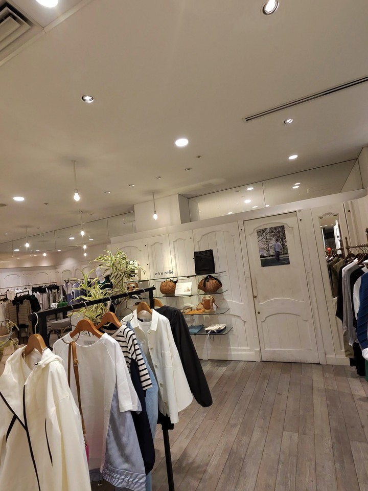 カジュアルな衣類を展示したレールと壁際に飾られたバッグなどの小物