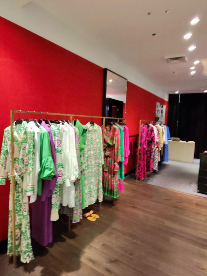 レッドカラーの壁に彩られた店内で色鮮やかな衣服がディスプレイ
