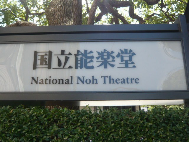 生垣の上に国立能楽堂の標識があります。判り易いです。
