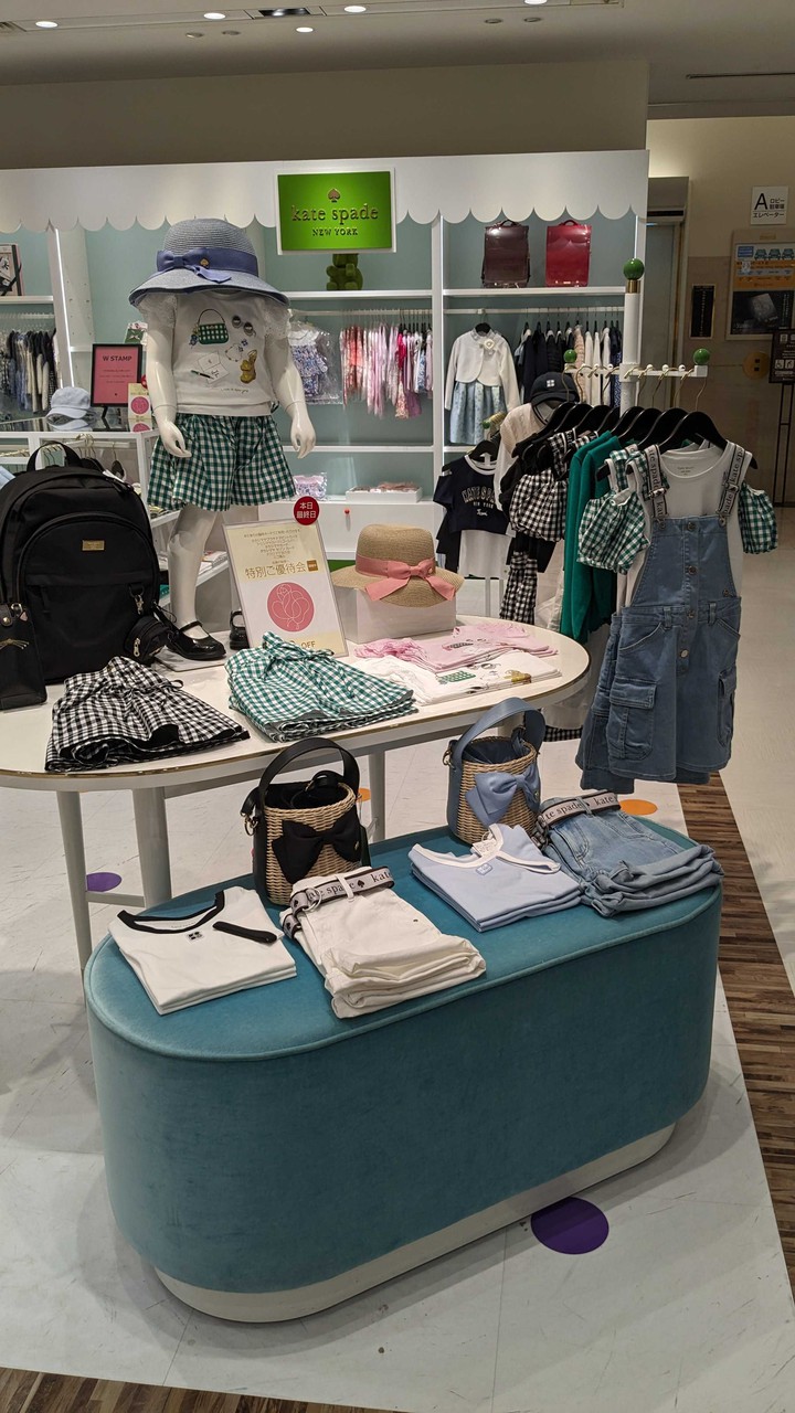kate spade new york kidsで展示されているトレンディな子供服。チェック柄のスカート、デニムオーバーオール、ストライプのハットなどが特徴的です。