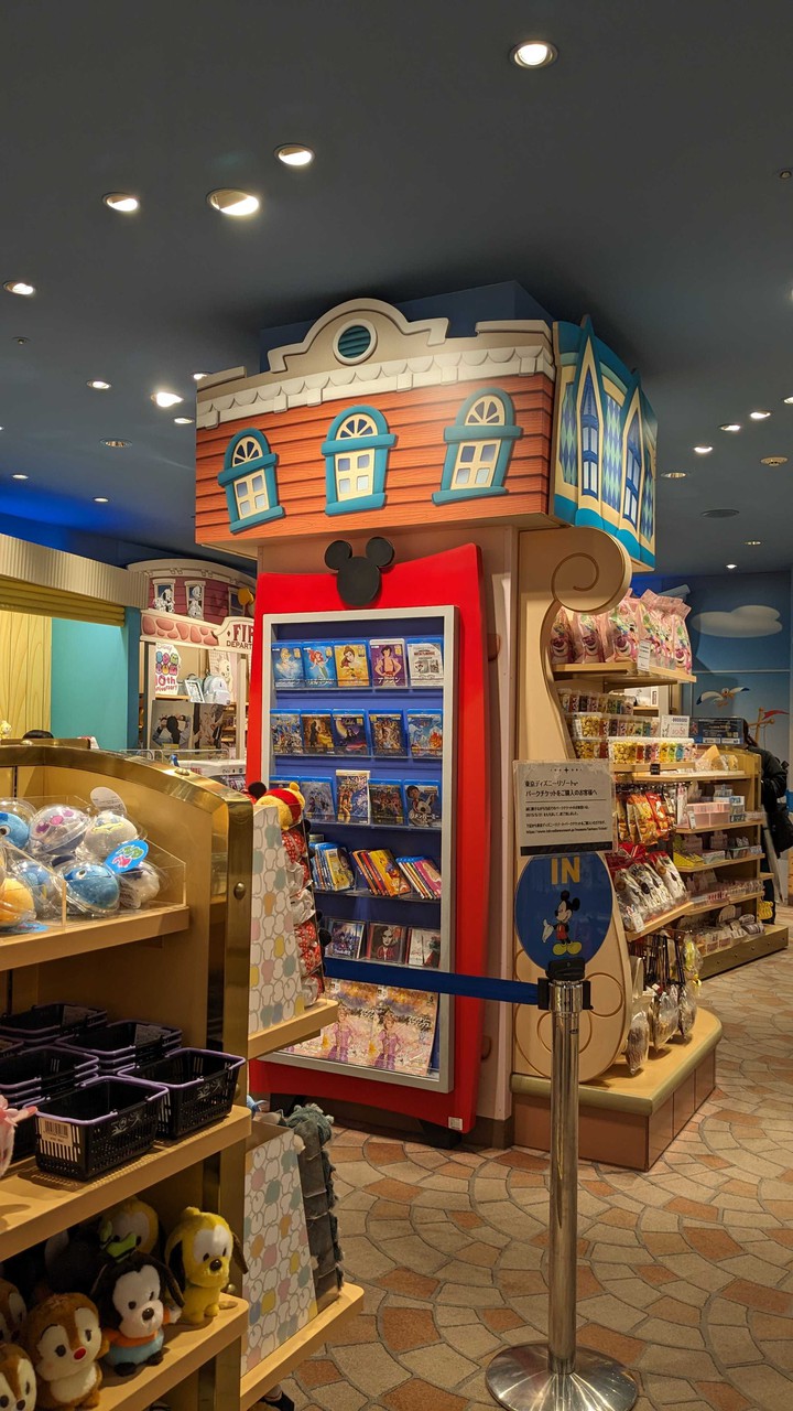 Disney storeでミッキーマウスのデザインが特徴の赤い棚にディズニー映画のDVDとグッズが展示されている