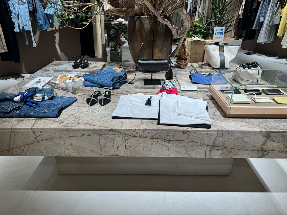 カオス店内のセンターテーブルにデニムとアクセサリーがディスプレイされている様子。テーブルの上には、大きな木と花が飾られています。