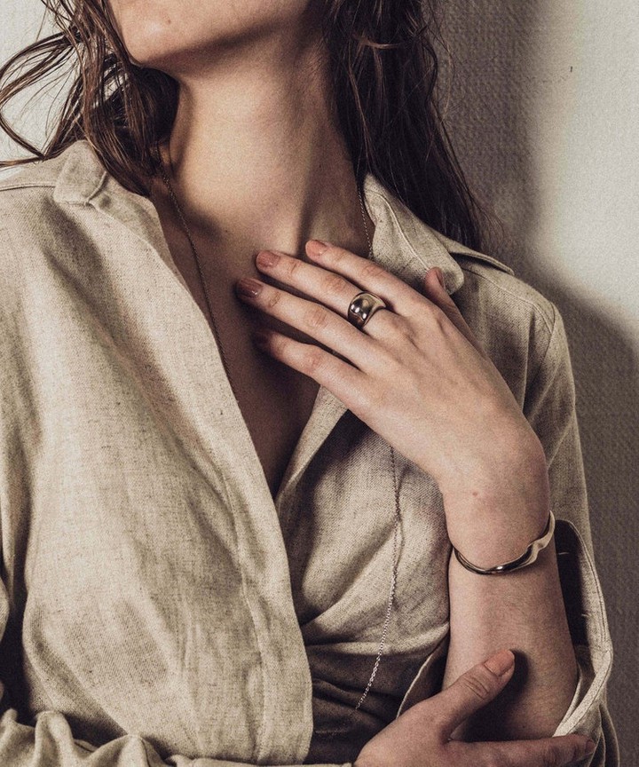 シンプルさに遊び心を加えたジュエリーをつけた女性の画像。