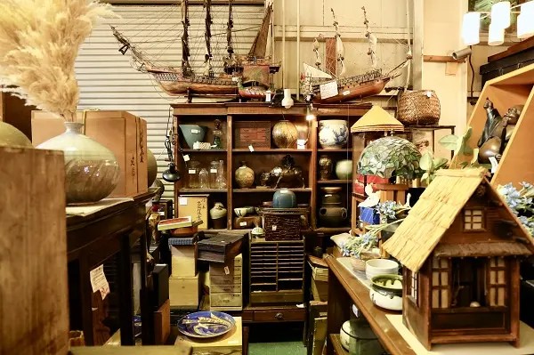 リサイクルショップの装飾品コーナー。古い船の模型や陶器が棚に展示されています