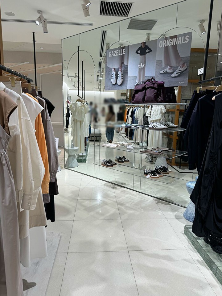 「emmi」のショップ内、モダンな服とが並ぶ洗練されたディスプレイ。