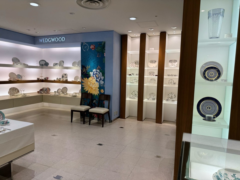 ウェッジウッドの陶磁器が展示されているショールームの内部。壁には青と白の磁器プレートや装飾品が並んでいる。後方の壁にはテーブルウェアが並ぶ棚が見える。