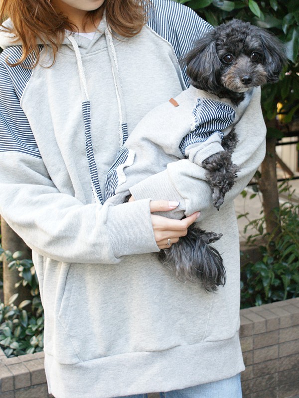 袖部分がブルーストライプになっているおそろいの白いウェアを着ている飼い主と犬