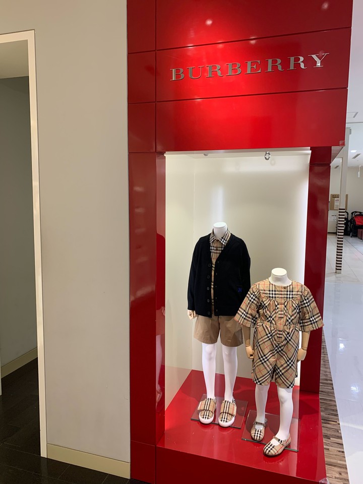 バーバリーブランドの赤いディスプレイボックス内には、バーバリーチェックの半袖ドレスを着た子供用マネキンが設置されています。